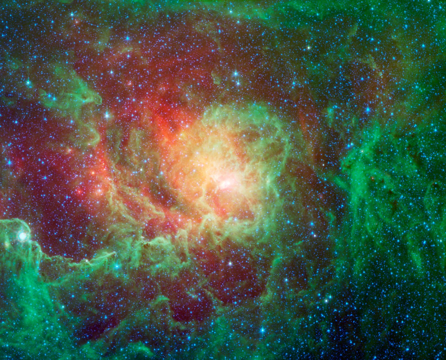 Image infrarouge de la nébuleuse de la Lagune M 8 dans la constellation du Sagittaire par le télescope spatial Spitzer : de vastes nuages de gaz striés de bandes de poussière sombres et des centaines d'étoiles nouvellement formées.