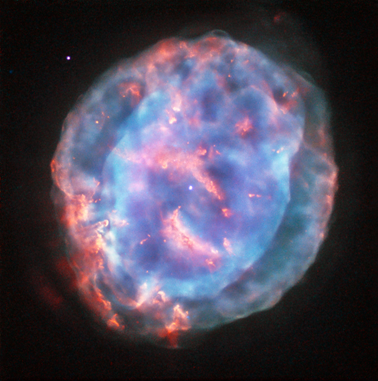 Image de Hubble de la nébuleuse planétaire NGC 6818 dans la constellation du Sagittaire : une bulle de gaz d'un bleu-vert lumineux, légèrement allongée, avec une zone interne plus brillante sur fond noir.
