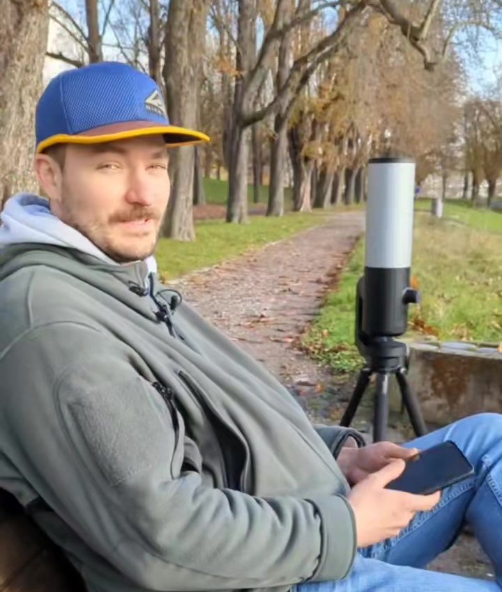 Alexander Merz von Sterngucker.de sitzt mit dem Smartphone neben dem Smart-Teleskop Unistellar eVscope 2