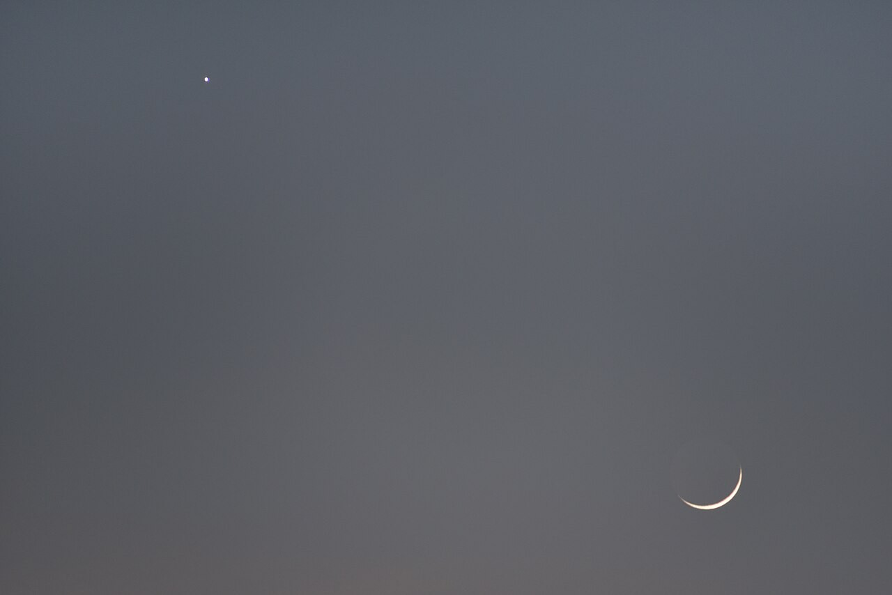 Heller Stern neben dem Mond: Venus steht über der schmalen Mondsichel in der Abenddämmerung