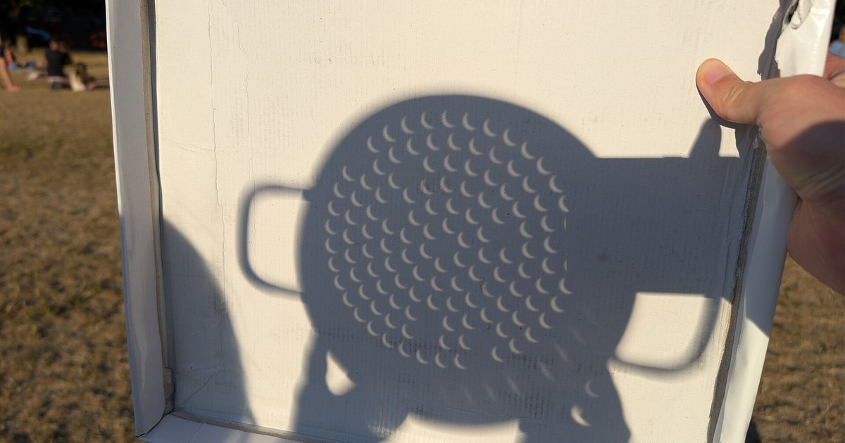 Sonnensicheln im Schatten eines Nudelsiebs während der Sonnenfinsternis
