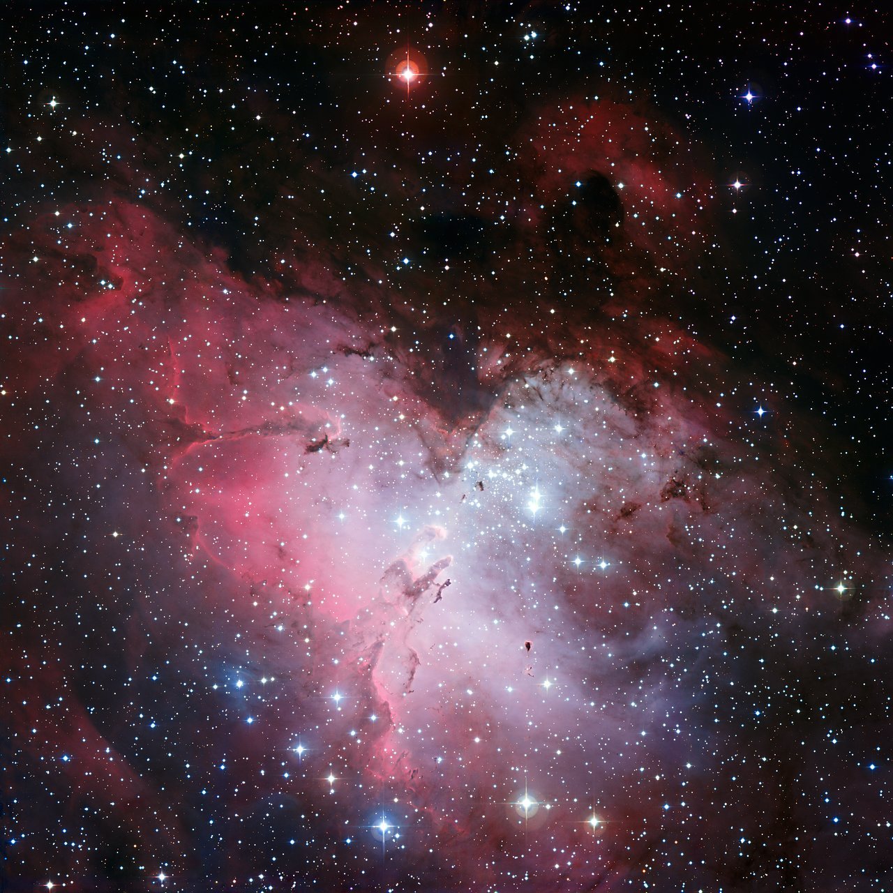 Der Adlernebel M16 im Weitfeld: rot leuchtende Gaswolke mit dem Sternhaufen NGC 6611 oben rechts und den kleinen Säulen der Schöpfung in der Mitte