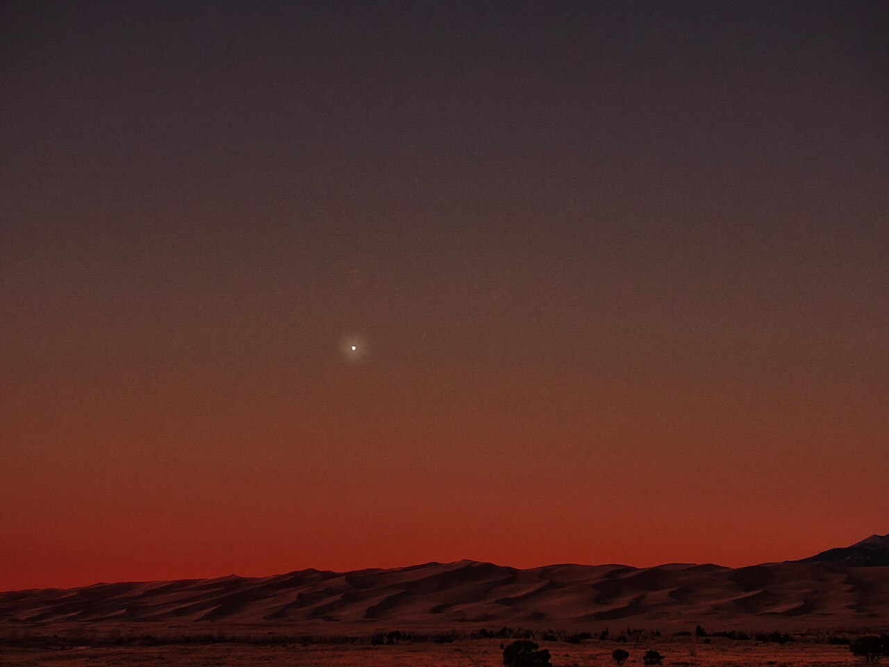 Heller Stern am Abendhimmel: die Venus leuchtet über den Dünen im Abendrot
